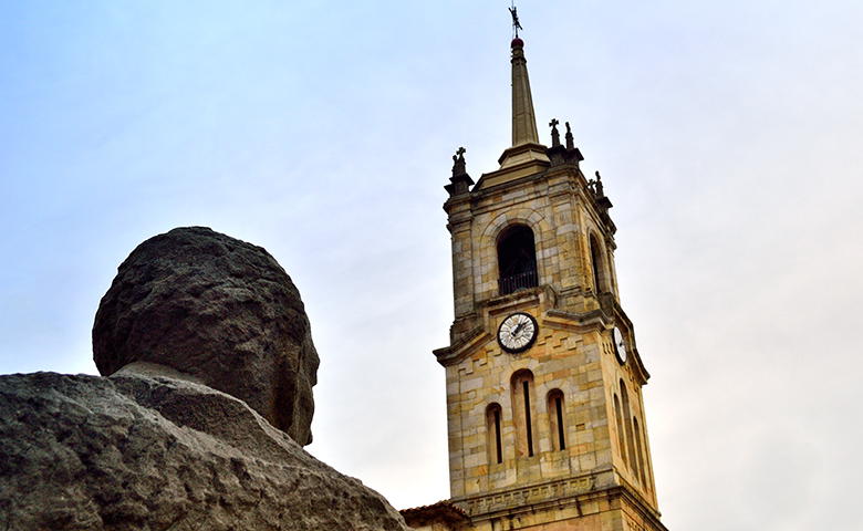 Busto del profesor Grande Covián mirando hacia la iglesia de Colunga