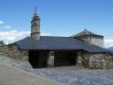 Iglesia rústica de piedra con tejado de pizarra y espadaña bajo un cielo despejado