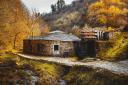 An old stone forge next to a river in a rural setting