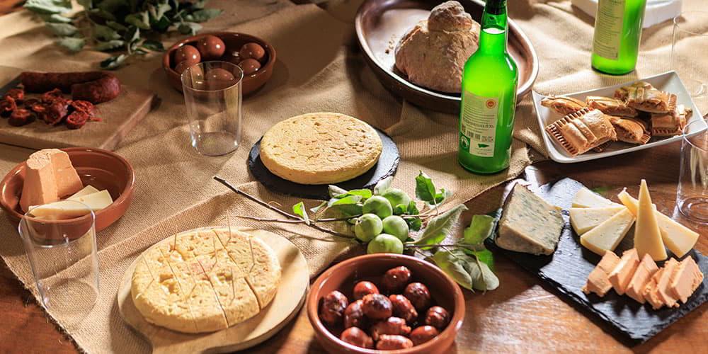 Tisch mit asturischen Käsesorten, Chorizo in Cidre, Wurstwaren und traditionellen Produkten, die mit asturischem Cidre kombiniert werden.