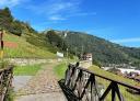 View of the Lloreo recreation area from the path, with a footbridge and a mountainous background.