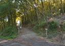 Signposted crossroads towards San Martín de Oscos on the Senda Verde, with a walker.