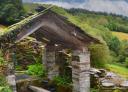 Traditional washhouse in San Mamed, covered in wood and stone, in a rural setting.