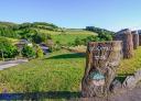 Stone carved sign of the Ecomuseo del Pan, overlooking green Asturian meadows.