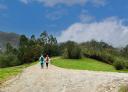 Couple of hikers at a crossroads surrounded by green meadows and forest.
