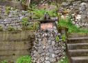 Stone fountain with sign 'Fuente de La Pimpana' between rock walls