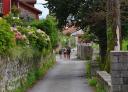 Hikers entering the village of Pendueles through a street lined with flowers.