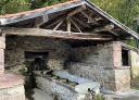 Traditional stone washhouse under wooden roof in Soto de Agues