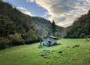 Stone cottage in a meadow surrounded by forest on the Alba route