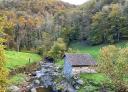 Riverside cabin amidst autumn woodland on the Alba Route