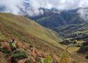 Hiker climbing up green slopes towards Collada Imblenes