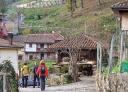 Hikers passing through Campiellos next to an Asturian hórreo (granary).