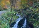 Small waterfall of the river Raigosu amidst autumn vegetation