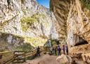 Group with helmet accessing the Huerta Cave between limestone walls.
