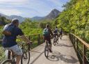 Group of cyclists cycling along the footbridge next to the Valdemurio reservoir.