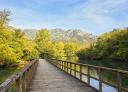 Wooden footbridge over the Valdemurio reservoir with mountains in the background