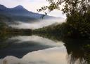 Reflection of mountains and mist on the Valdemurio reservoir at dawn