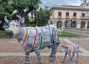 Esculturas de vaca y ternero pintadas con escenas urbanas en plaza de Vegadeo