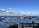 Vista del cartel en primer plano con el mar y rocas en medio del agua en el fondo