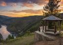 Mirador con pérgola de madera con vistas a un río y un atardecer