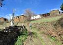Senderista ascendiendo por un camino rural de tierra cerca de casas de piedra