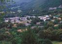Aerial view of a village in a green valley surrounded by vegetation.