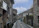 Hiker walking along a cobbled street with houses on either side of him