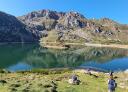 Hikers enjoy views of a mountain lake and valley on a sunny day.