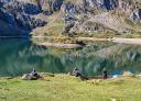 Hikers sitting on the shore of a mountain lake.