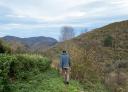 Hiker walking along a path with a mountainous landscape in the background.