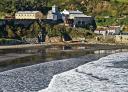 Playa de Arnao, con olas rompiendo y el museo al fondo