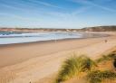 Vaste plage de sable avec dunes et mer sous un ciel dégagé
