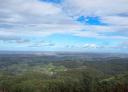 Panorama showing a vast wooded landscape under a blue sky with clouds