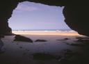 Natural rocky arch on the beach with sea view and wet sand