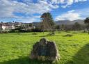 Gran roca en un campo verde bajo un cielo azul claro con nubes