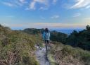 Una persona camina por un sendero estrecho en la cima de la montaña con vistas panormámicas al mar