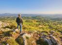 A hiker contemplates the views of a landscape from a high point.
