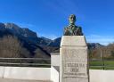 Bronze bust on a stone pedestal with mountains in the background