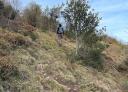 Hiker climbing up a steep, narrow path on the hillside.