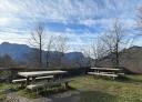 Rest area with wooden tables and benches and mountains in the background.