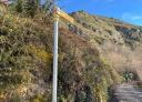 Close-up of a signpost with a couple of hikers on a path.