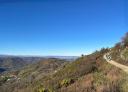 Panoramic view of the landscape and a group of hikers walking along a path on a hillside.