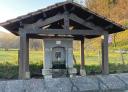 A traditional stone fountain under a rustic wooden roof