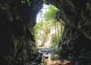 Cave mouth and outside light entering, forming silhouette of the rocky tunnel