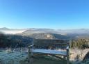 Wooden bench in viewpoint, with valleys and mountains shrouded in winter mist