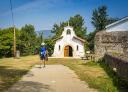 A hiker observes a small white chapel.