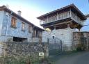 Traditional Asturian granary of wood and stone next to a rural house.