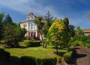 Large historic house with lush garden and bright blue sky