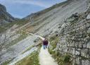 Un couple de randonneurs marche le long d'un mur de pierre.