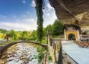 Acceso al santuari bajo unas rocas junto a un río y un puente